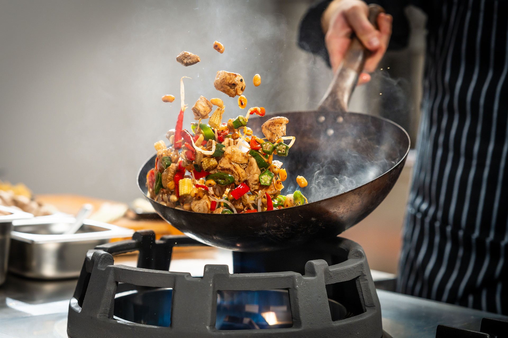 Cook stir frying vegetables and meat in a wok